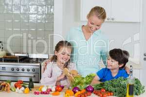 Mother and kids preparing a salad in kitchen