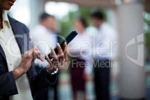 Mid section of female business executive using mobile phone