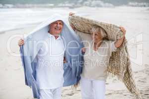 Senior couple holding shawl over head