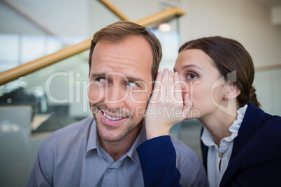 Ã?Â Businesswoman whispering something to her colleague