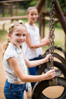 Happy girl smiling while holding a swing in park