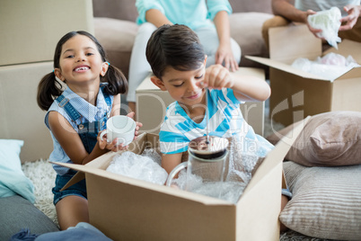 Kids unpacking carton boxes in living room at new home