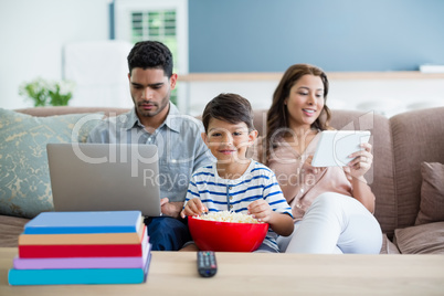 Portrait of boy with mother and father using laptop and digital tablet in background