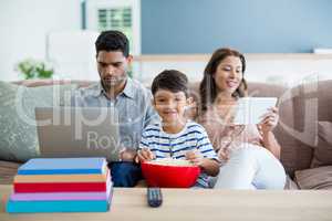 Portrait of boy with mother and father using laptop and digital tablet in background