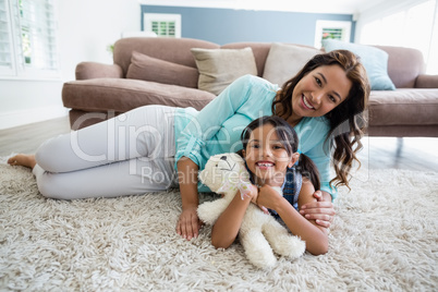 Portrait of happy mother and daughter lying on rug