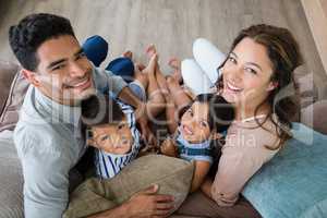 Portrait of happy parents and kids sitting on sofa in living room