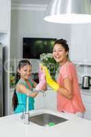 Mother and daughter giving high five in kitchen at home
