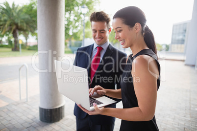 Businessman and colleague discussing over laptop