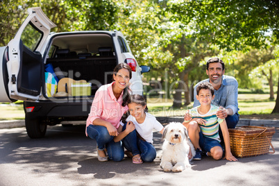 Happy family on a picnic sitting next to their car