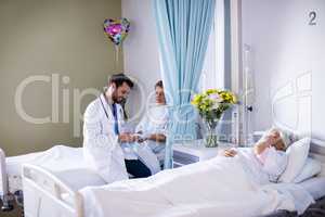 Male doctor interacting with female senior patient in the ward