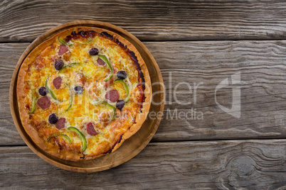 Italian pizza served in a pizza tray on a wooden plank