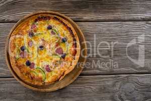 Italian pizza served in a pizza tray on a wooden plank