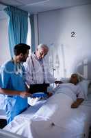 Doctors discussing a medical report with patient on bed