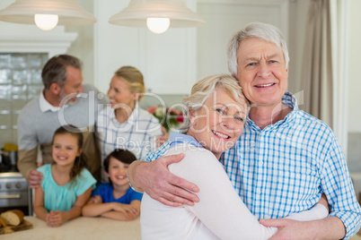 Portrait of happy senior couple embracing each other in kitchen