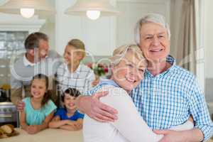 Portrait of happy senior couple embracing each other in kitchen