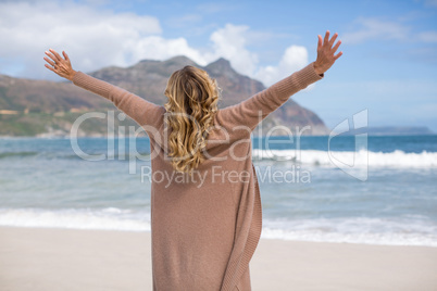 Mature woman with arms outstretched standing on the beach