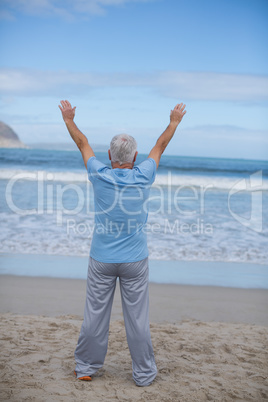 Senior man doing stretching exercise on the beach