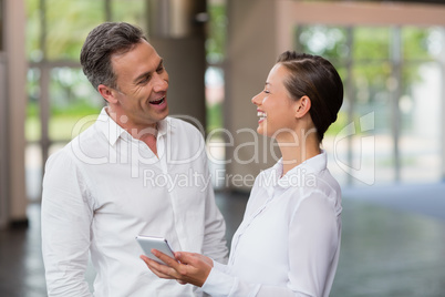 Business executives discussing over mobile phone and laughing