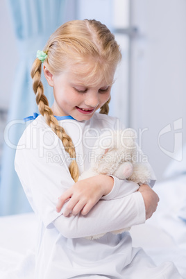 Sick girl with teddy bear in hospital bed