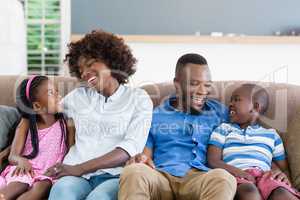 Parents and kids interacting while sitting on sofa in living room
