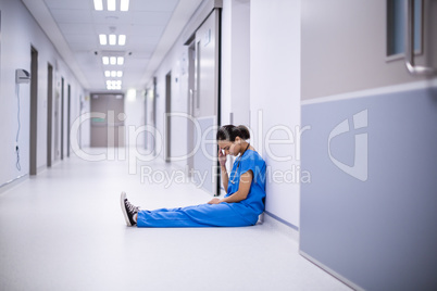 Tensed female doctor sitting in corridor