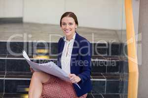 Businesswoman sitting on steps holding blueprint