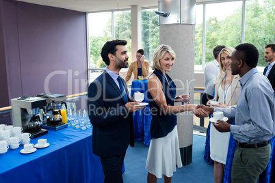 Business executives interacting with each other while having coffee