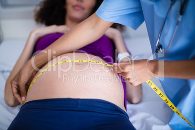 Doctor measuring pregnant womans belly in ward