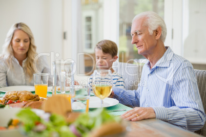 Multi-generation family praying before having meal