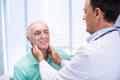 Doctor examining senior patients neck