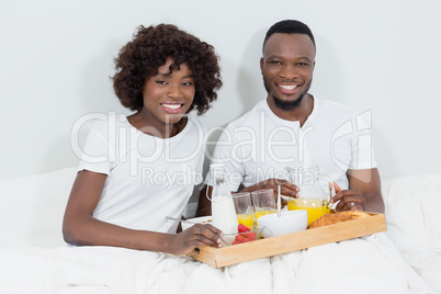 Portrait of smiling couple having breakfast in bedroom