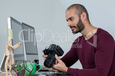 Photographer sitting at desk holding camera