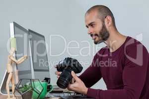 Photographer sitting at desk holding camera