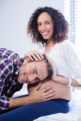 Smiling man listening to pregnant womans belly in ward