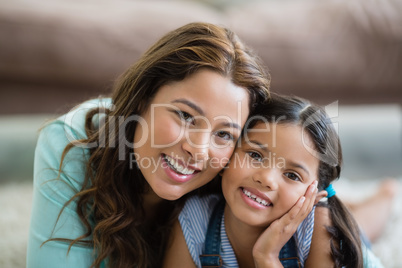 Portrait of happy mother and daughter lying in living room
