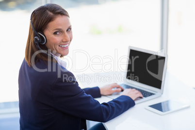 Businesswoman wearing headphone using laptop