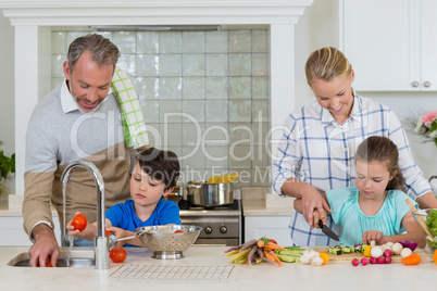 Parents assisting a kids to chop and clean the vegetables in kitchen