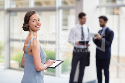 Cheerful businesswoman holding digital tablet at conference centre