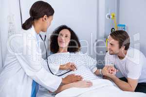 Doctor examining pregnant woman in ward