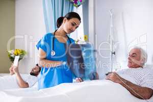 Female doctor discussing x-ray report with male senior patient in the ward