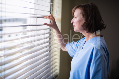 Thoughtful nurse looking out through window