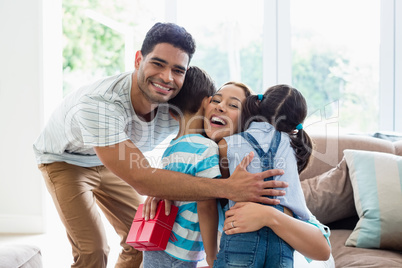 Mother receiving a gift from his kids and husband in living room