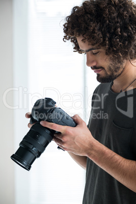 Male photographer reviewing captured photos in his digital camera