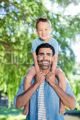 Father carrying son on his shoulders park