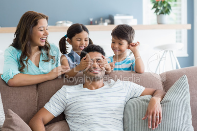 Girl covering her father eyes while giving surprise in living room