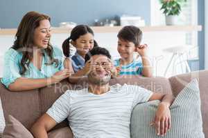 Girl covering her father eyes while giving surprise in living room