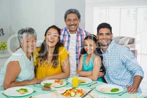 Happy multi generation family having meal on table at home