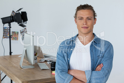 Smiling photographer standing with his arms crossed in studio