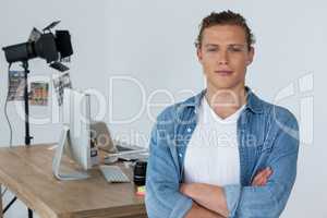 Smiling photographer standing with his arms crossed in studio