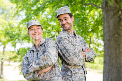 Military couple standing with arms crossed in park